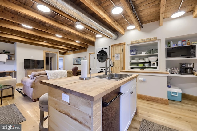 1700 N Texter Mountain Rd, Reinholds, PA 17569 - kitchen with butcher block countertops, black microwave, stacked washer and clothes dryer, a sink, and wood ceiling with exposed beams