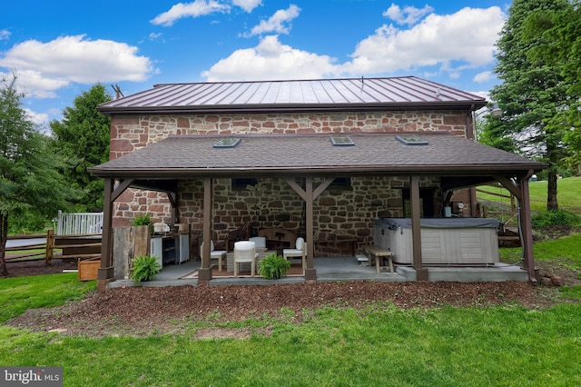 1700 N Texter Mountain Rd, Reinholds, PA 17569 - back of property featuring a standing seam roof, a patio area, stone siding, and a hot tub