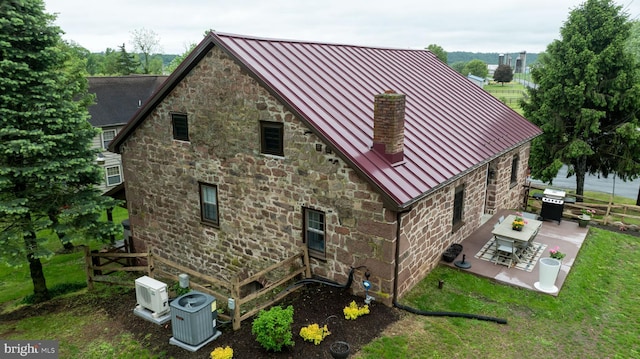 1700 N Texter Mountain Rd, Reinholds, PA 17569 - back of property featuring a standing seam roof, metal roof, a patio area, central AC unit, and stone siding