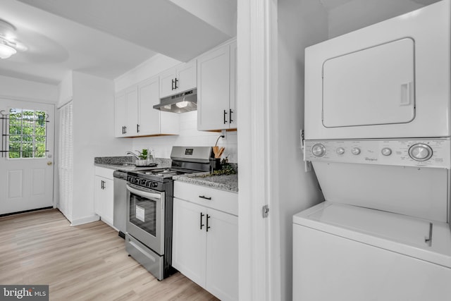 4428 Edson Pl NE, Washington, DC 20019 - kitchen featuring stainless steel appliances, stacked washing machine and dryer, under cabinet range hood, white cabinetry, and light wood-style flooring