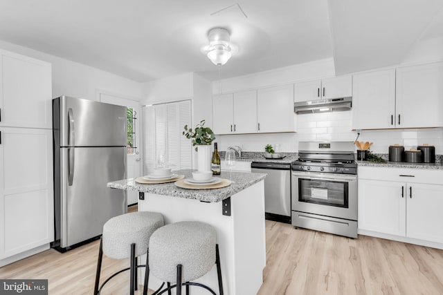 4428 Edson Pl NE, Washington, DC 20019 - kitchen featuring stainless steel appliances, under cabinet range hood, a breakfast bar area, white cabinetry, and light wood-style floors
