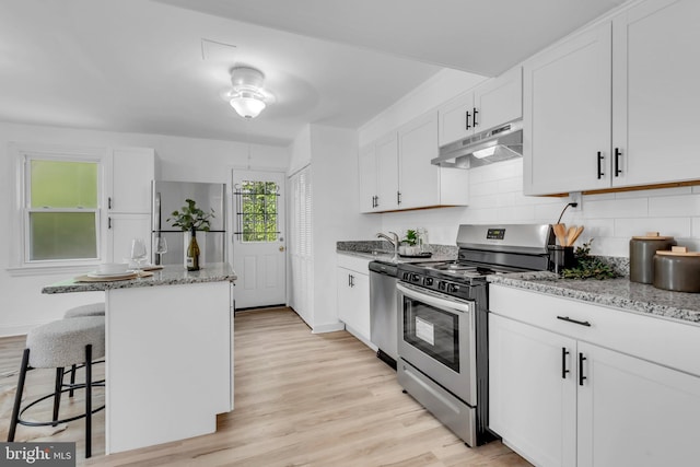 4428 Edson Pl NE, Washington, DC 20019 - kitchen featuring stainless steel appliances, under cabinet range hood, a sink, light wood-style floors, and a kitchen island