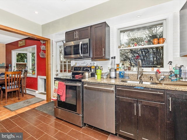 kitchen with appliances with stainless steel finishes, a sink, decorative backsplash, dark brown cabinets, and recessed lighting