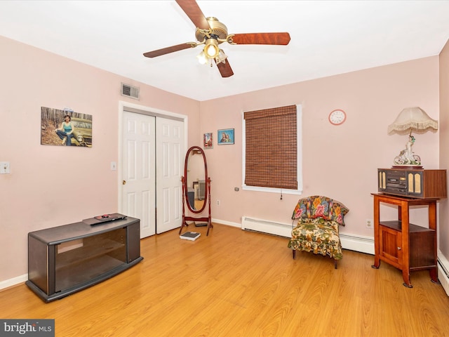 sitting room with ceiling fan, light wood finished floors, baseboard heating, and baseboards