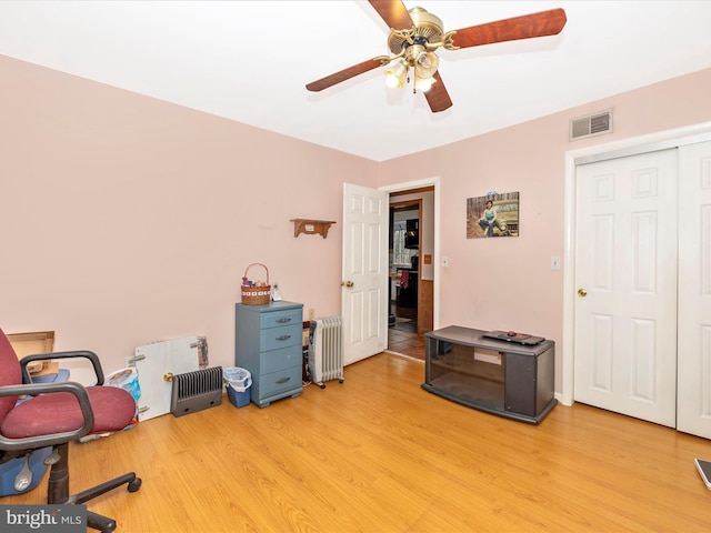 office space with radiator heating unit, ceiling fan, and light wood finished floors