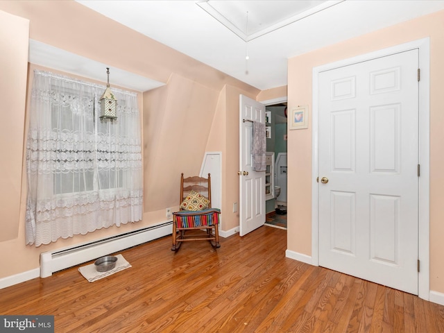 sitting room with baseboard heating, attic access, wood finished floors, and baseboards