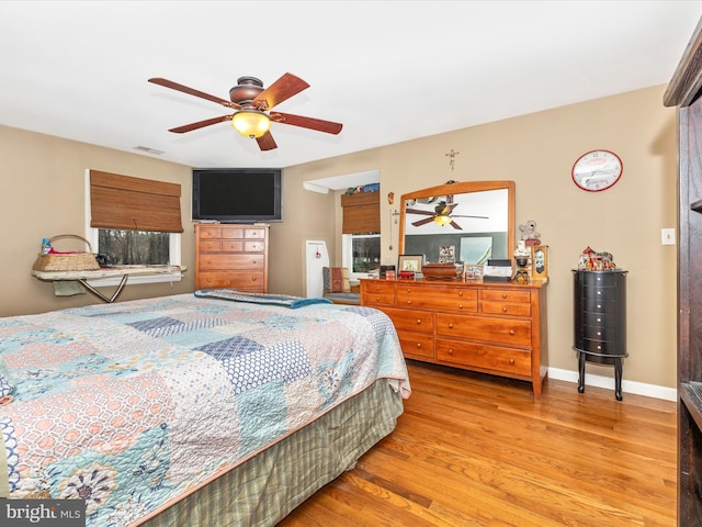 bedroom with light wood-style flooring, ceiling fan, and baseboards