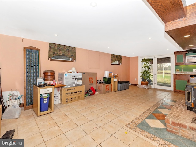 below grade area featuring a sink, tile patterned flooring, a wood stove, and recessed lighting