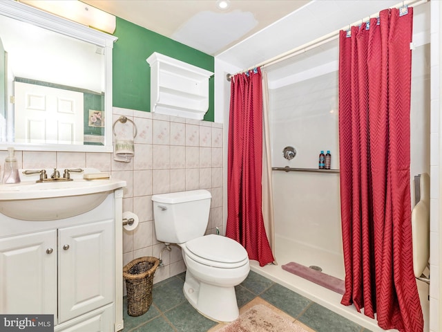 bathroom featuring tile walls, a shower stall, toilet, vanity, and a wainscoted wall