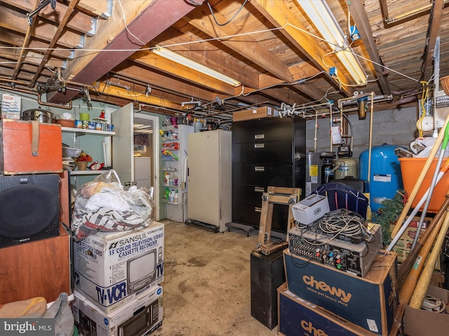 unfinished basement featuring a water pressure tank, water heater, and freestanding refrigerator