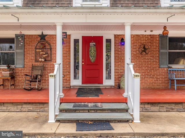 entrance to property with covered porch and brick siding
