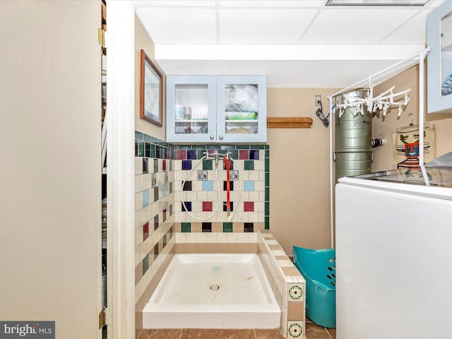 full bath featuring washer / clothes dryer, a stall shower, and tile patterned floors
