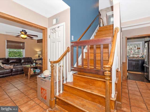 staircase with tile patterned floors and a ceiling fan
