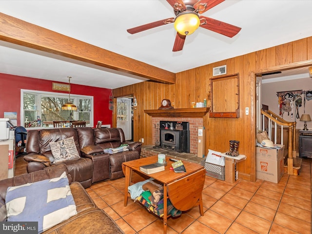 living area featuring wooden walls, beamed ceiling, light tile patterned flooring, and ceiling fan