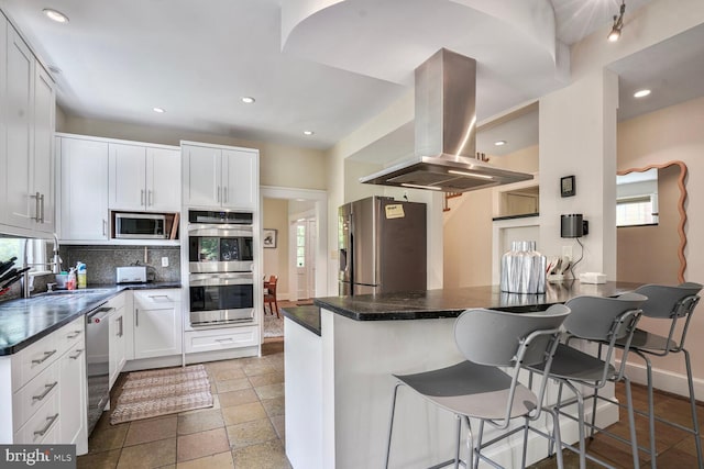 3707 Thornapple St, Chevy Chase, MD 20815 - kitchen featuring island range hood, stainless steel appliances, tasteful backsplash, dark countertops, and a kitchen breakfast bar