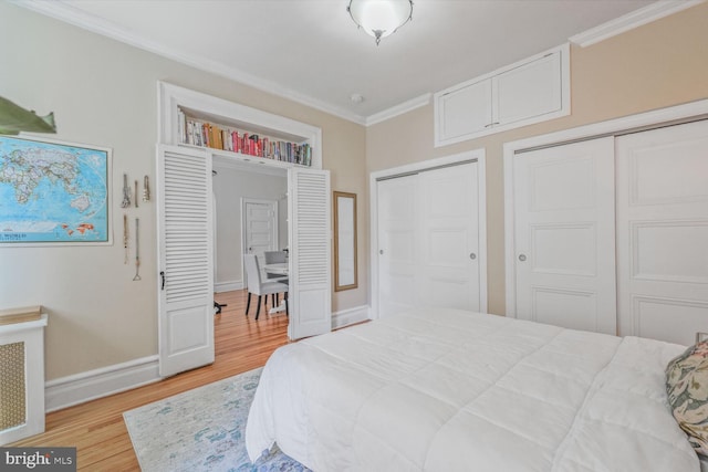 bedroom with crown molding, multiple closets, light wood-style floors, and baseboards