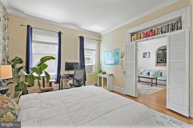 bedroom with crown molding, wood finished floors, and baseboards