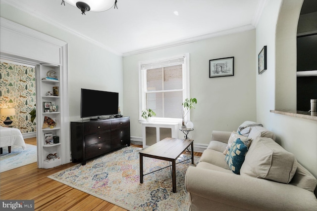 living area featuring wood finished floors, crown molding, radiator, arched walkways, and baseboards