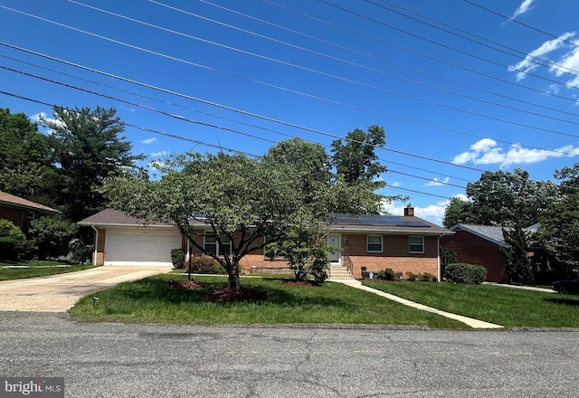 view of front of home with brick siding, solar panels, concrete driveway, and a front lawn