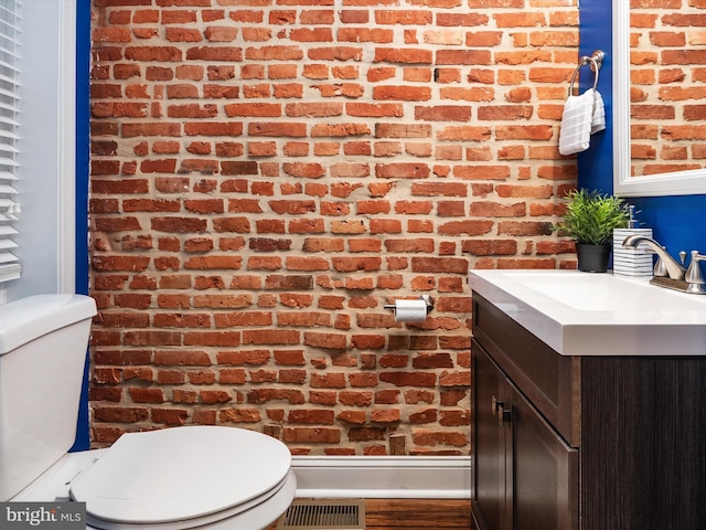 628 E Fort Ave, Baltimore, MD 21230 - bathroom featuring brick wall, toilet, vanity, and wood finished floors