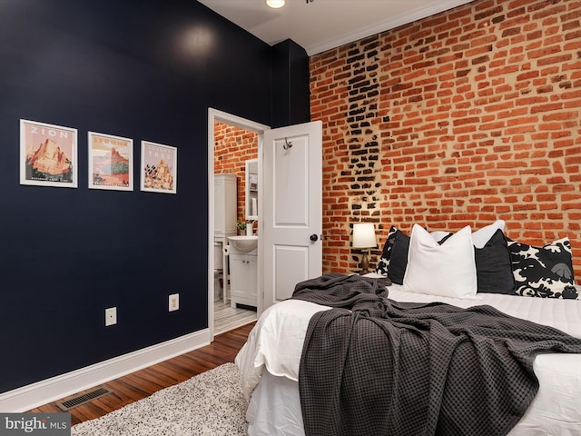 628 E Fort Ave, Baltimore, MD 21230 - bedroom featuring wood finished floors, brick wall, connected bathroom, and baseboards