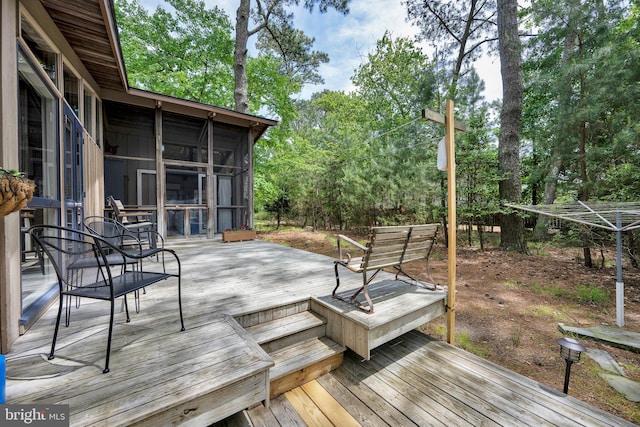 17 Robins Ln, Rehoboth Beach, DE 19971 - deck featuring a sunroom, outdoor dining space, and view of wooded area