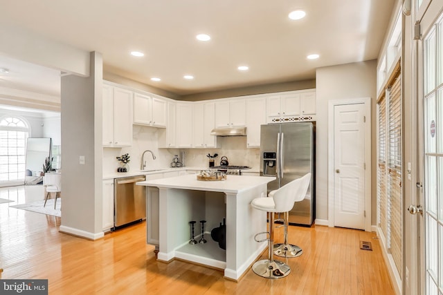 9093 Acheson Ct, Lorton, VA 22079 - kitchen with stainless steel appliances, under cabinet range hood, white cabinetry, light wood-type flooring, and recessed lighting