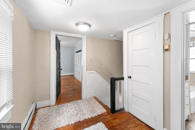 1838 Muddy Gut Rd, Dunnsville, VA 22454 - hall featuring a baseboard radiator, an upstairs landing, wood finished floors, a baseboard heating unit, and wainscoting