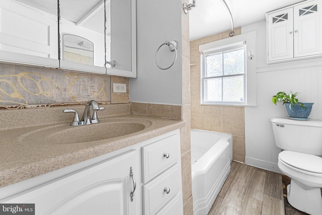 1838 Muddy Gut Rd, Dunnsville, VA 22454 - bathroom featuring toilet, vanity, wood finished floors, a bath, and backsplash