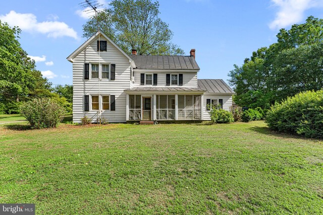 1838 Muddy Gut Rd, Dunnsville, VA 22454 - view of front of property featuring a chimney, a sunroom, a front lawn, a standing seam roof, and metal roof