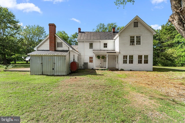 1838 Muddy Gut Rd, Dunnsville, VA 22454 - rear view of house with a lawn, a storage unit, a shingled roof, and an outbuilding