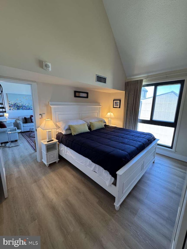 911 Harbour House Rd Unit 911, Bethany Beach, DE 19930 - bedroom with wood finished floors, high vaulted ceiling, a textured ceiling, and baseboards