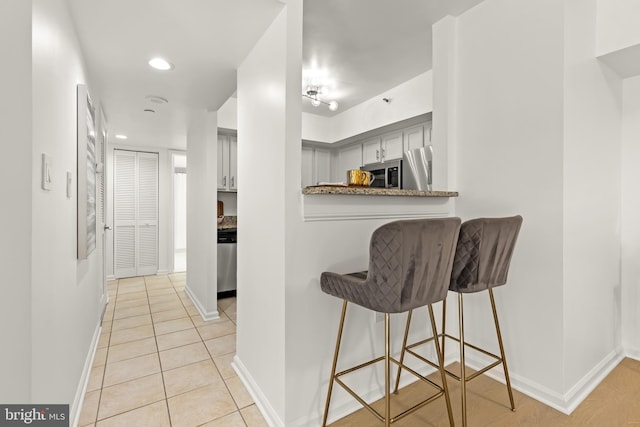 1001 N Randolph St Unit 910, Arlington, VA 22201 - kitchen with appliances with stainless steel finishes, a breakfast bar area, baseboards, light tile patterned flooring, and recessed lighting
