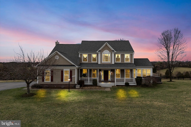 rear view of property featuring a porch, a chimney, a yard, and a shingled roof