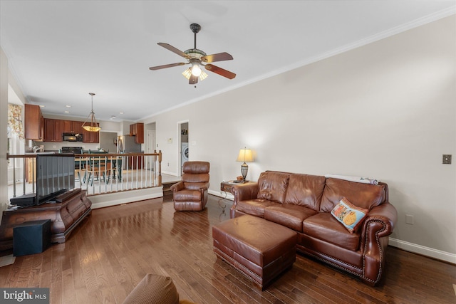 living area with ornamental molding, ceiling fan, hardwood / wood-style floors, baseboards, and washer / dryer