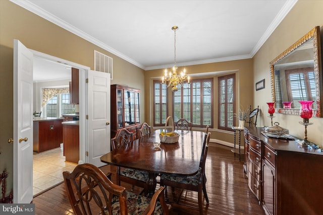 dining space featuring ornamental molding, a chandelier, hardwood / wood-style flooring, and baseboards