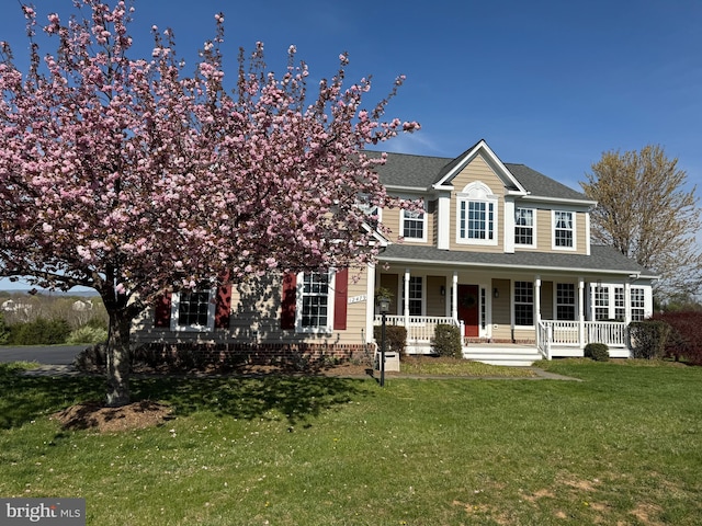 view of front facade featuring a porch, a front yard, and roof with shingles