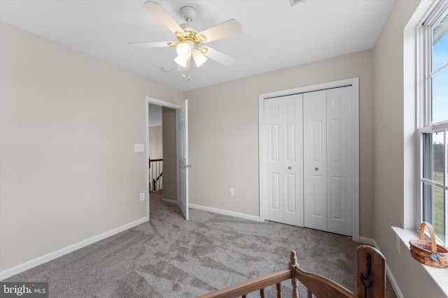 carpeted bedroom with a closet, baseboards, and ceiling fan