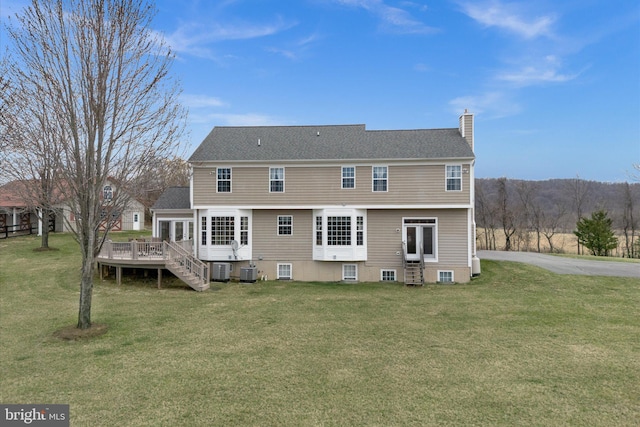 rear view of house featuring a chimney, a deck, a lawn, entry steps, and central AC unit
