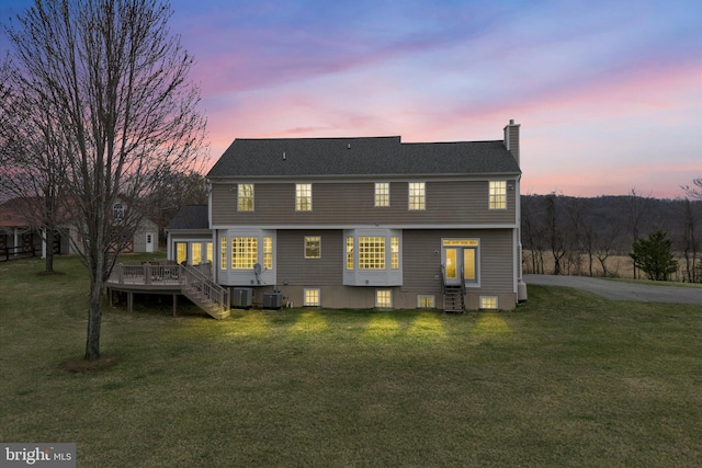 back of house featuring a chimney, a deck, a lawn, and entry steps