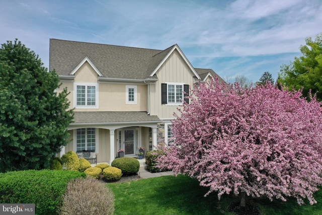 8 Fallbrook Ln, Glen Mills, PA 19342 - view of front of house with covered porch, board and batten siding, a shingled roof, stone siding, and a front lawn