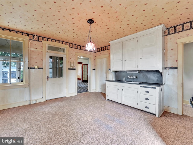 45 Front St, Lititz, PA 17543 - kitchen featuring wallpapered walls, dark countertops, white cabinetry, pendant lighting, and a sink
