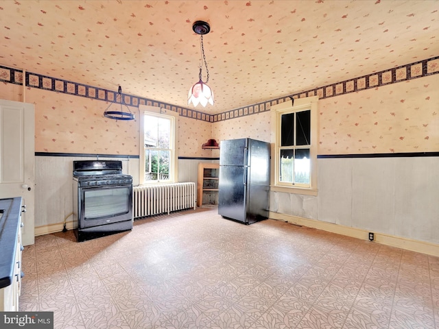 45 Front St, Lititz, PA 17543 - kitchen featuring freestanding refrigerator, radiator heating unit, range with gas cooktop, wallpapered walls, and a wainscoted wall