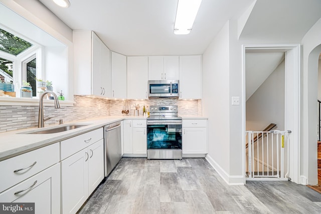 600 Saint Andrews Ln, Silver Spring, MD 20901 - kitchen featuring appliances with stainless steel finishes, a sink, light wood-style floors, backsplash, and white cabinetry