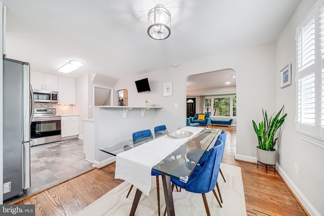 600 Saint Andrews Ln, Silver Spring, MD 20901 - dining room featuring arched walkways, light wood-style flooring, and baseboards
