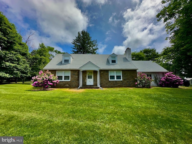 cape cod house featuring stone siding, a chimney, and a front yard