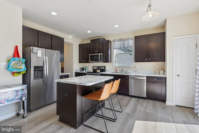 430 Mcwharton Way, Bunker Hill, WV 25413 - kitchen with appliances with stainless steel finishes, light wood-style flooring, dark brown cabinetry, a kitchen island, and a kitchen bar