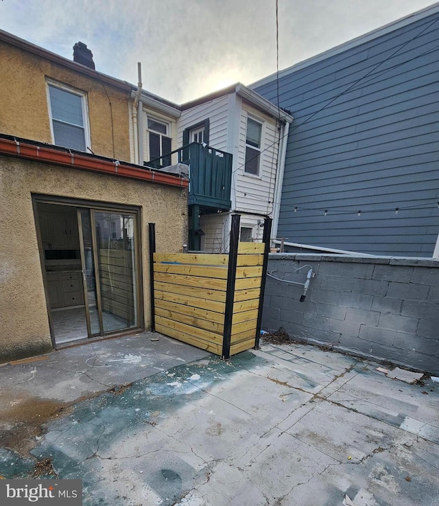3404 Mueller St, Baltimore, MD 21224 - back of house featuring a balcony, stucco siding, a chimney, and a patio area