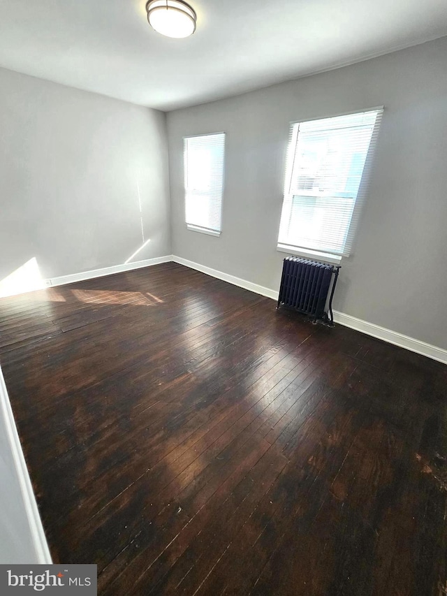 3404 Mueller St, Baltimore, MD 21224 - unfurnished room featuring radiator heating unit, dark wood finished floors, and baseboards