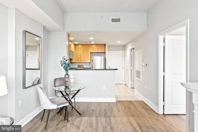 3600 S Glebe Rd Unit 605W, Arlington, VA 22202 - kitchen featuring appliances with stainless steel finishes, light wood-style floors, light brown cabinetry, dark countertops, and a peninsula